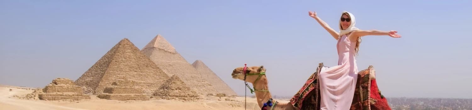 Desconectarse en Egipto frente a las Pyramids de Giza Un viajero feliz recorre el desierto en camello frente a las pirámides de Giza.
